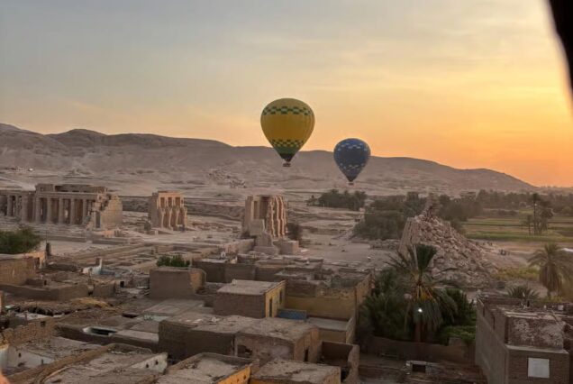 Hot air balloons over Luxor, Egypt at sunrise, with sweeping views of the Nile River, temples, and desert landscape.