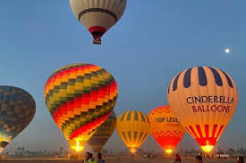 "Hot air balloons flying over Luxor, Egypt, with views of the Nile, Hatshepsut Temple, and the Valley of the Kings at sunrise."