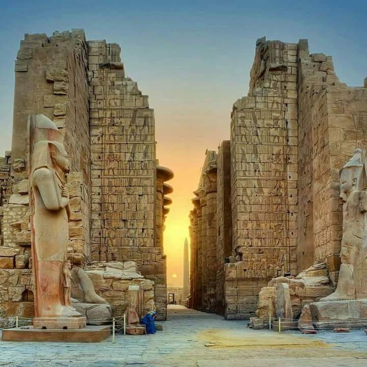 Luxor Temple on the east bank of the Nile, featuring colossal statues and sandstone columns illuminated by sunlight.